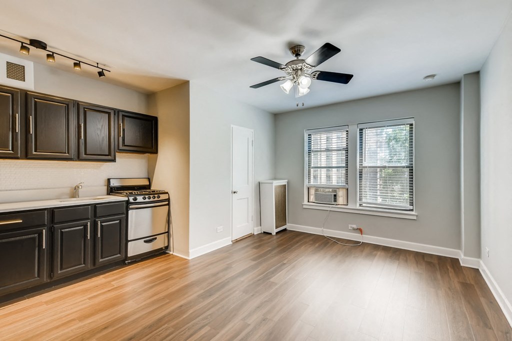 an empty kitchen with wood floors and a ceiling fan