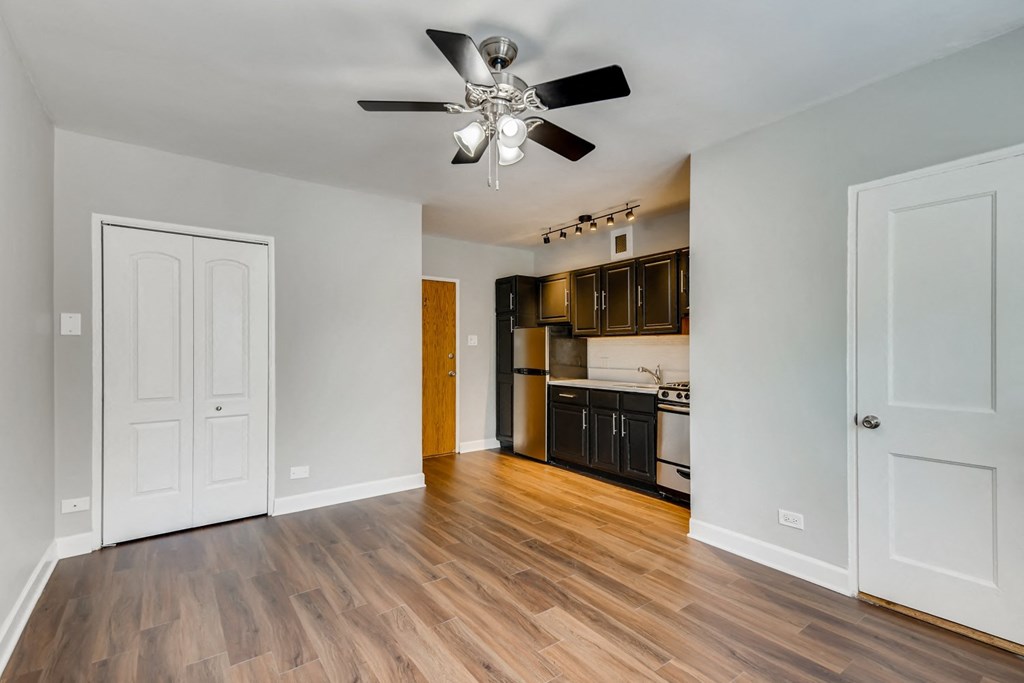 an empty living room with a ceiling fan and a kitchen