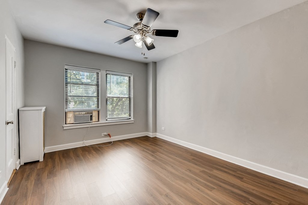 an empty living room with wood floors and a ceiling fan