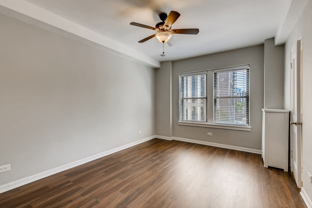 an empty living room with a ceiling fan and a window