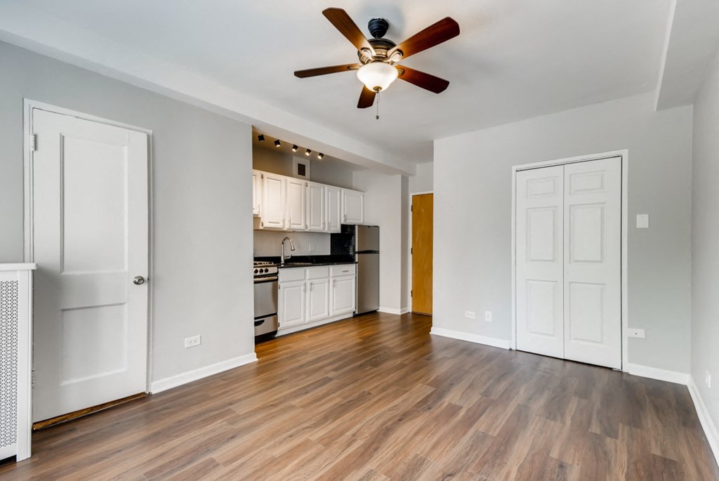 an empty living room with a ceiling fan and a kitchen