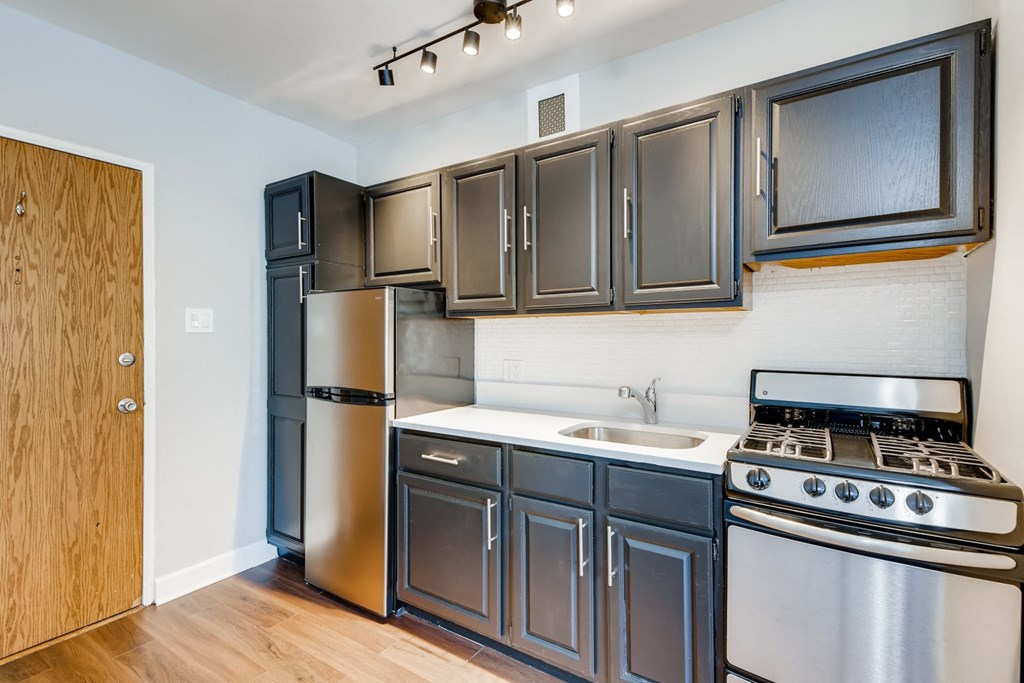 an empty kitchen with stainless steel appliances and dark cabinets