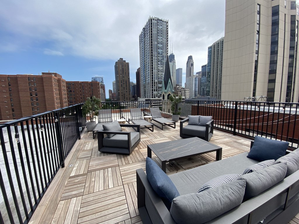 a roof deck with couches and tables and a view of the city