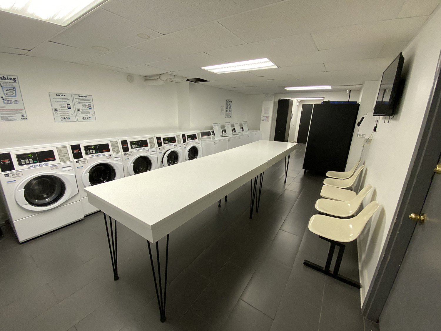an empty laundry room with washing machines and a table with chairs