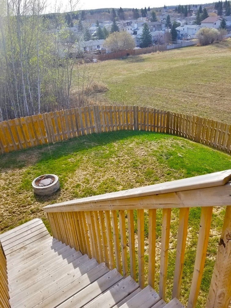 a backyard with a wooden fence and a grass field