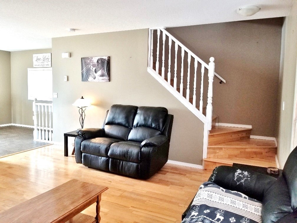 a living room with leather furniture and a staircase