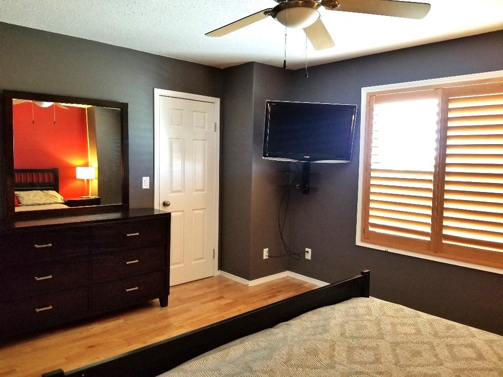 a bedroom with a tv and a dresser and a window