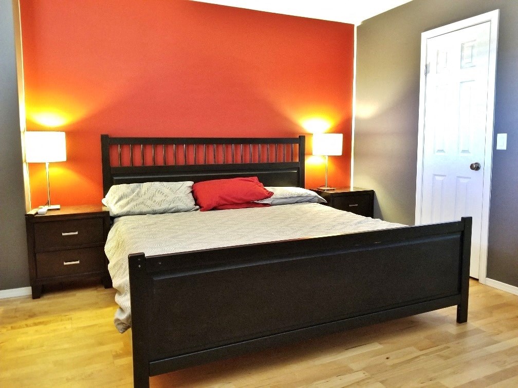 a bedroom with an orange accent wall and a bed