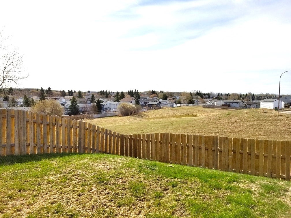 a backyard with a wooden fence and a field