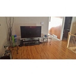 A living room with a television and a glass table.