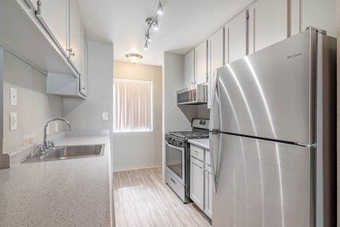 A modern kitchen with a stainless steel refrigerator and a sink with a faucet.