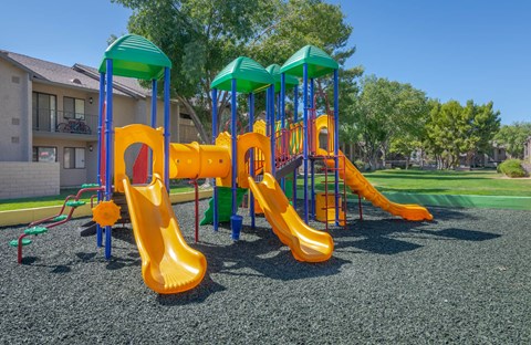 A playground with a yellow slide and green canopies.