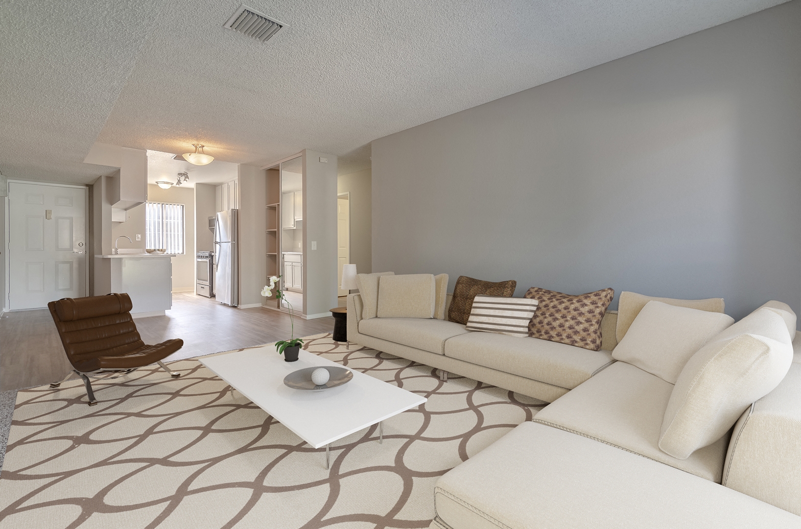 A living room with a white couch and a brown chair.