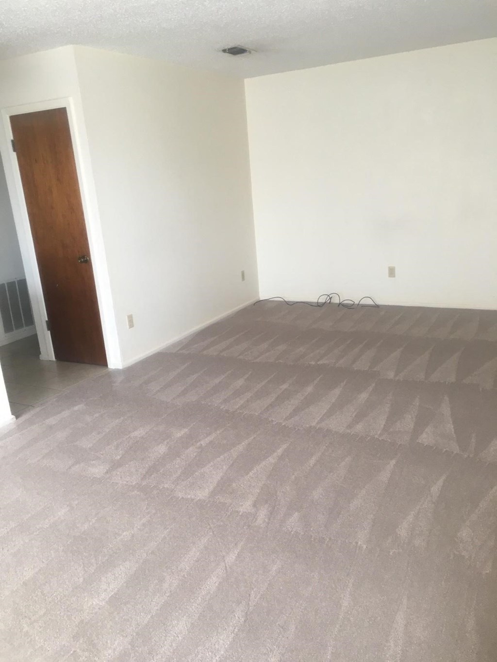 an empty living room with a carpeted floor and a door