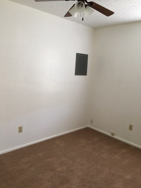 an empty room with a ceiling fan and white walls