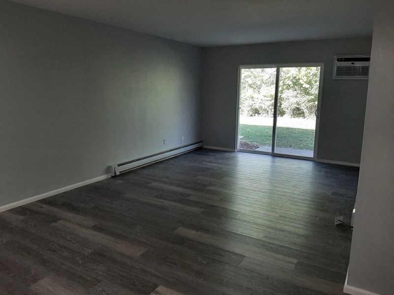 A room with a sliding glass door leading to a green outdoor area.