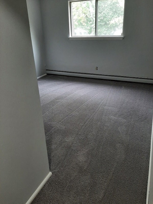 A room with a carpeted floor and a window.