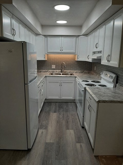 A kitchen with white cabinets and a refrigerator.