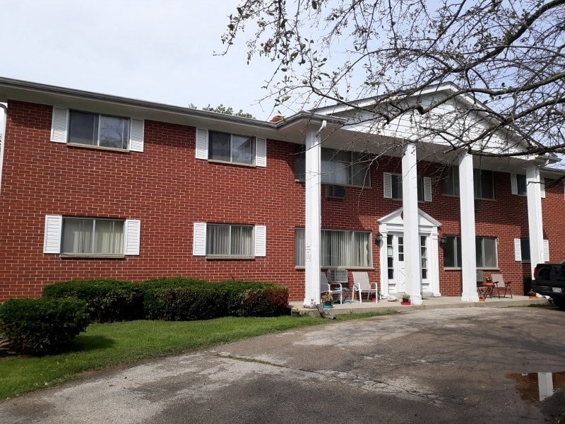 A red brick building with white columns and a white door.