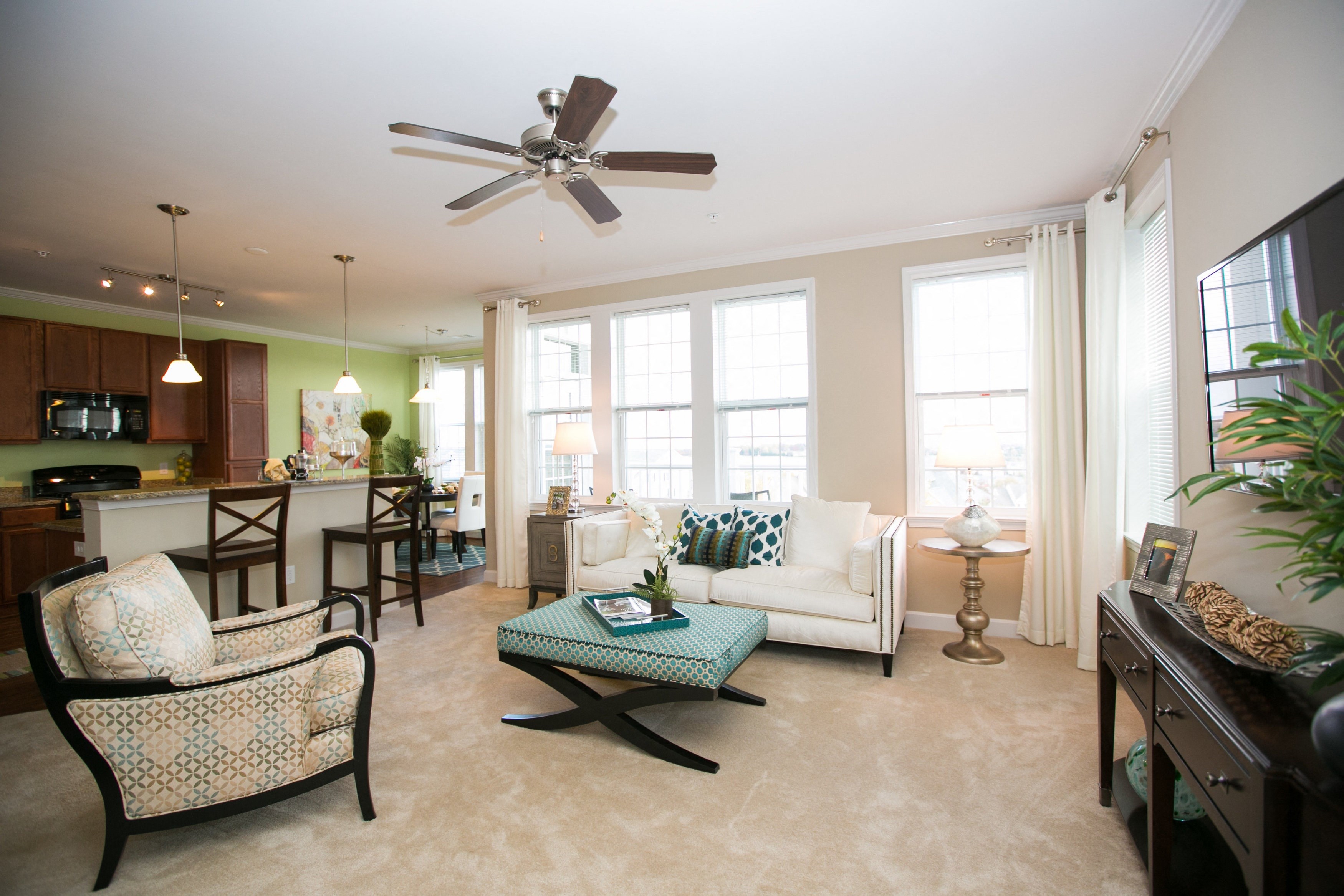 living room at VistaView apartments in Frederick, MD with couch, chairs, coffee table, console table and wall mounted TV, and view of counter seating