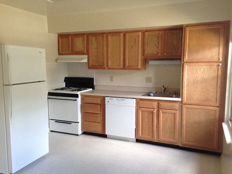 an empty kitchen with white appliances and wooden cabinets