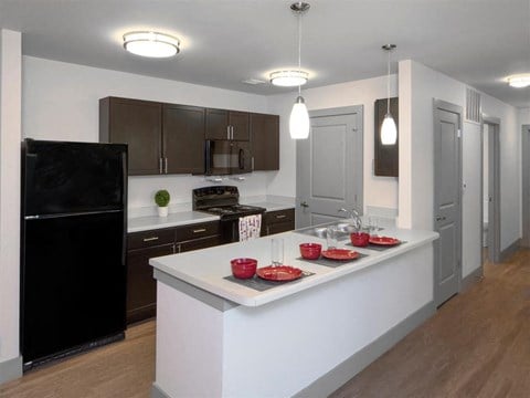 a kitchen with a white counter top and a black refrigerator