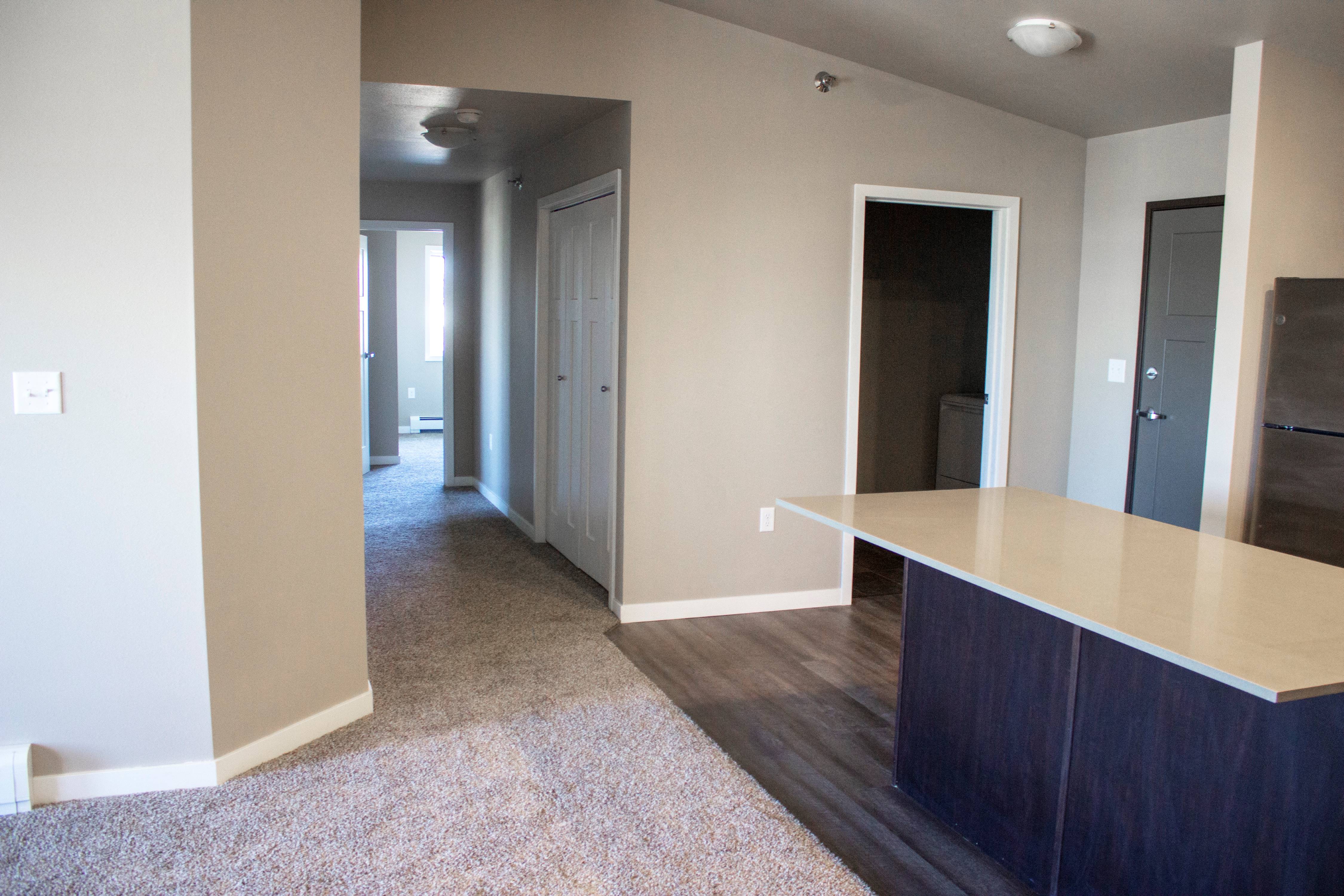 a living room with a kitchen and a hallway with a door to a bedroom