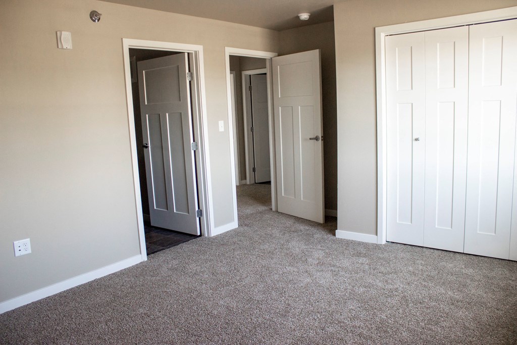 an empty room with three doors and a carpeted floor