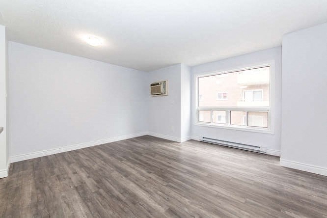 an empty living room with a large window and white walls