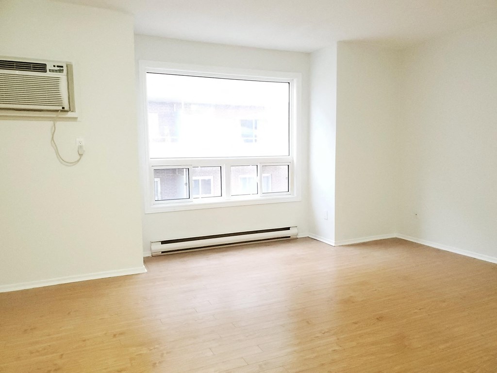 an empty living room with a window and wood floors