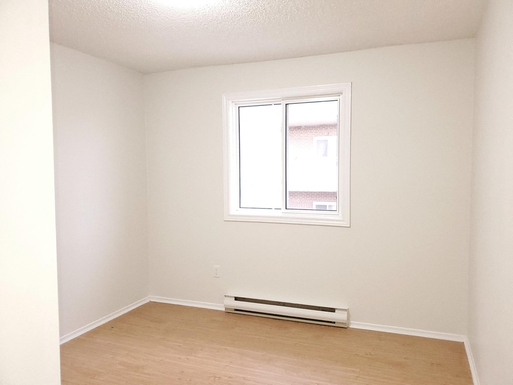 an empty room with a window and a wood floor