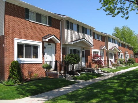A row of houses with a sidewalk in front.