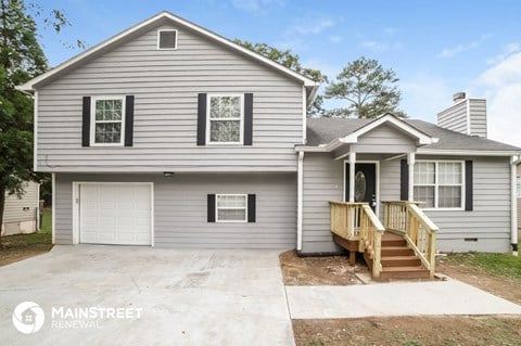 a gray house with a porch and a white garage door