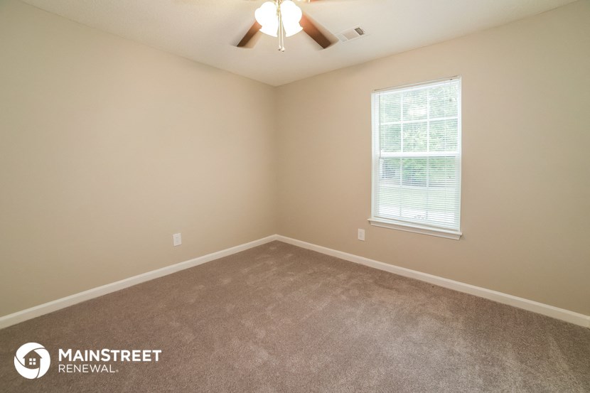 the upstairs bedroom has a carpeted floor and a ceiling fan