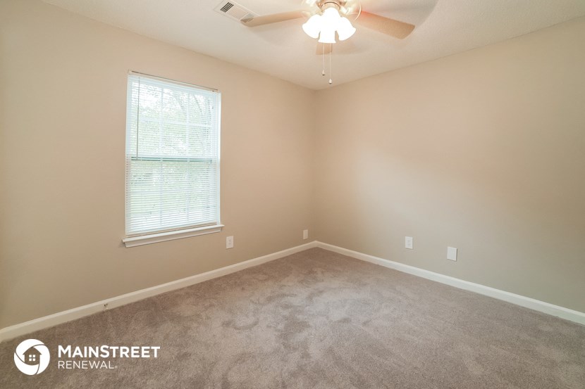 a carpeted room with a ceiling fan and a window