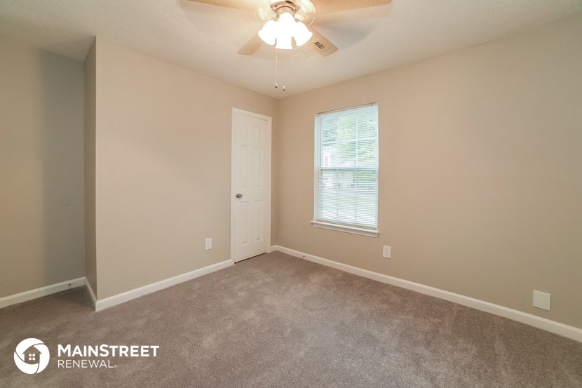 the spacious bedroom with carpeted flooring and a ceiling fan