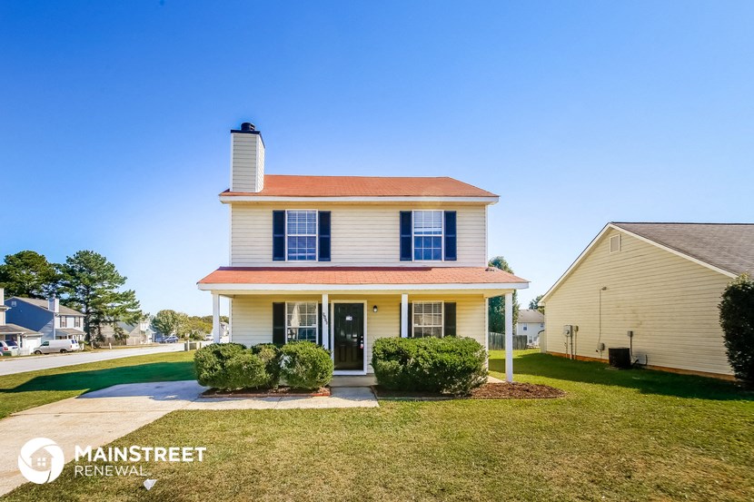 a white house with blue shutters and a lawn