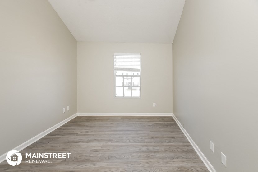 a spacious room with white walls and a window
