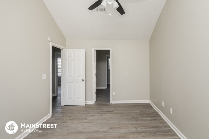 a living room with white walls and a ceiling fan
