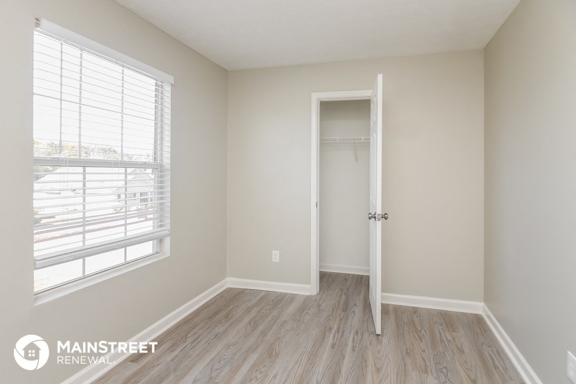 a bedroom with a door to a closet and a window