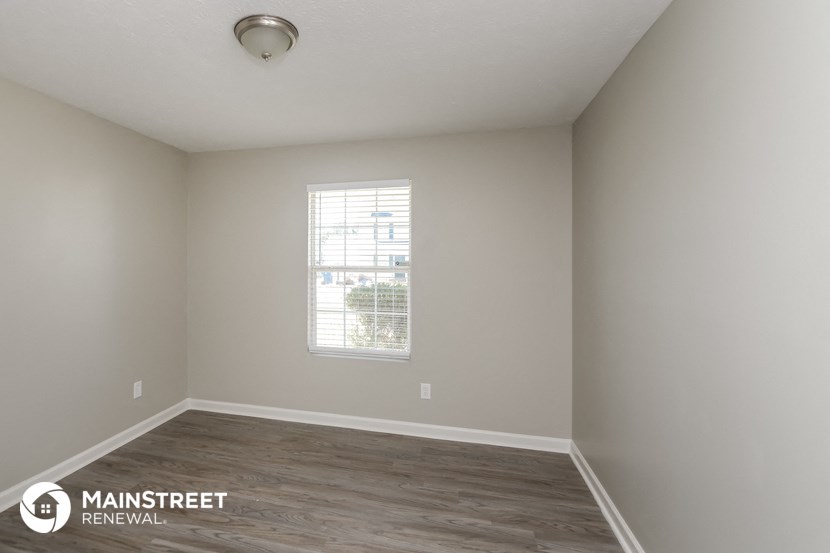 the interior of an empty room with wood flooring and a window