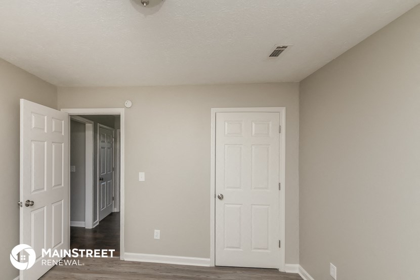 a bedroom with two white doors and a hallway to a closet
