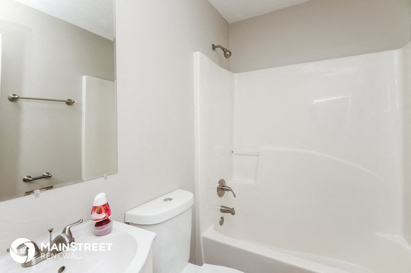a white bathroom with a white toilet and a tub and a sink