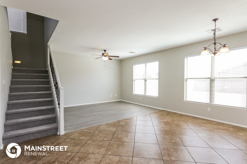 an empty living room with a staircase and a ceiling fan