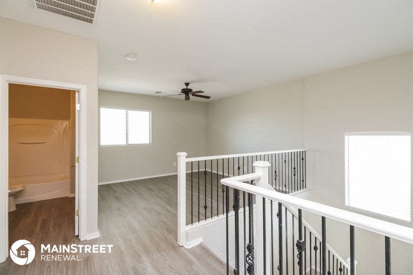 the upstairs landing of a renovated home with a ceiling fan