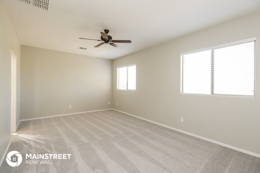 an empty living room with a ceiling fan and window
