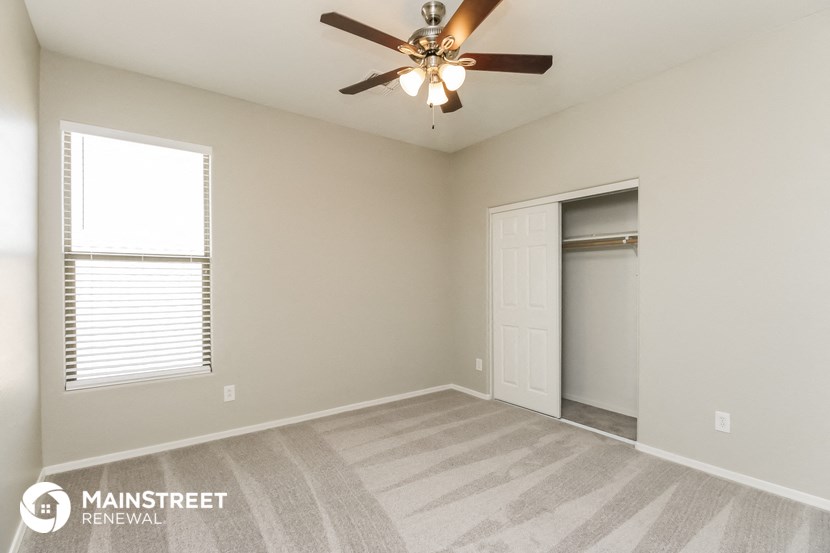 an empty living room with a ceiling fan and a closet