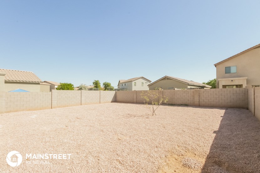 a large yard with a fence and houses in the background