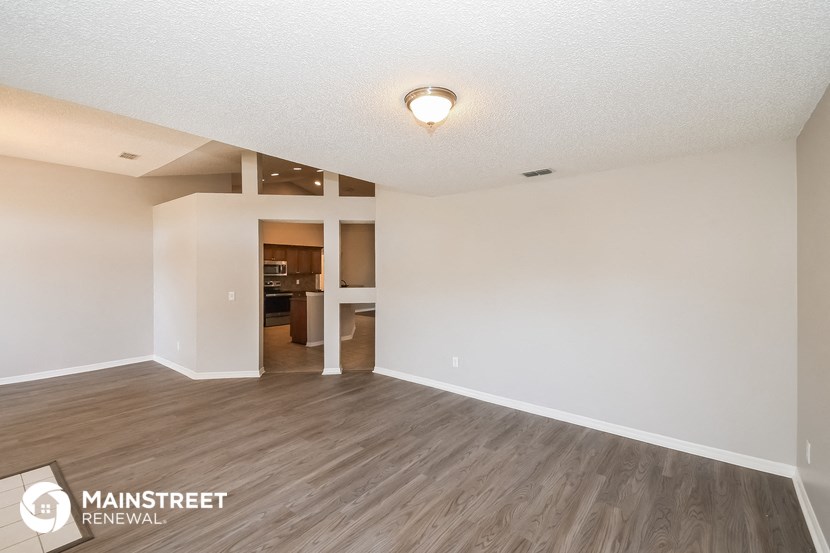 the spacious living room with hardwood flooring and white walls