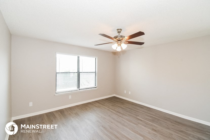 the spacious living room with ceiling fan and wood flooring
